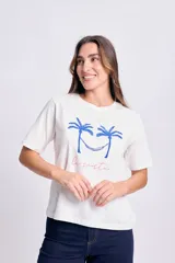 Remera blanca de manga corta con estampa de dos palmeras con una hamaca entre ellas y la frase "la siesta" en color rosa.