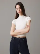 Remera de punto de viscosa elástica color blanco, con textura de canalé irregular, corte slim, cuello perkins y mangas raglán cortas.