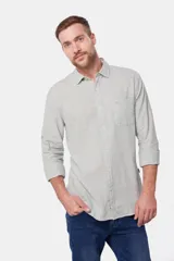 Camisa de lino color beige, de manga larga, con cuello clásico y bolsillo en el pecho.
