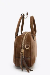 Bolso mini bowling color camel de serraje, con doble asa de mano y correa bandolera extraíble. Tiene un bolsillo interior con cremallera y cierre principal con cremallera y tirador.