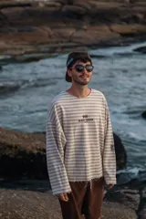 Buzo de manga larga reversible. Un lado es color arena con rayas horizontales marrones y el otro lado es azul marino liso.