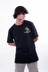 Remera oversized negra con diseño gráfico en la espalda, combinando tintas blanca y mostaza, y con grifa oficial en la manga.