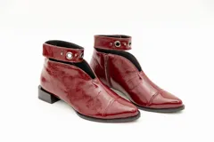 Botín de cuero color borgoña con taco bajo, corte en V en el empeine, pulsera con detalles metálicos y cierre lateral.