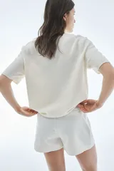 Cárdigan color crema de punto suave con lana en la trama. Modelo de manga corta con cuello redondo con ribete acanalado y botones brillantes adelante. Remate acanalado en puños y bajo.