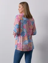 Camisa estampada con hojas en tonos celeste, naranja y verde. Tiene cuello con solapa, abertura central con botones, bolsillos aplicados en la parte delantera y mangas 3/4 con lazo.