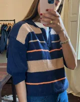 Sweater de punto con rayas horizontales en azul marino, beige y naranja. Tiene cuello polo y mangas 3/4 abullonadas.
