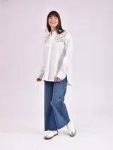 Camisa blanca de manga larga con detalles de encaje en los hombros.