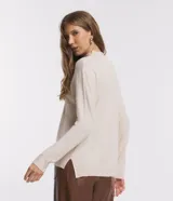 Blusa de punto color crema, con cuello alto y mangas largas.