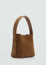 Bolso de mano marrón de piel serraje con asa corta ajustable y asa de hombro. Tiene forro interior, cierre de botón magnético y tamaño mediano.