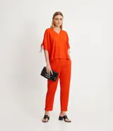 Blusa amplia color naranja, con escote en pico y mangas cortas con detalle de lazo fruncido.