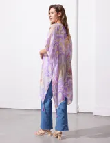 Kimono tejido con estampado abstracto en tonos verde, azul y blanco. Tiene mangas cortas amplias y terminación con borlas verdes en el ruedo.