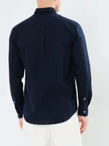 Camisa de popelina azul marino de Tommy Hilfiger, de manga larga, con cuello abotonado, cierre con botones y logo bordado en el pecho.