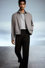 Pantalón negro de corte relajado, con cintura elástica ajustable con cordón, cierre con botón y corchete, bolsillos laterales y traseros.