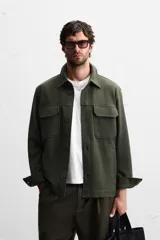 Sobrecamisa color beige de corte relaxed fit, con cuello solapa, manga larga con puños abotonados, bolsillos de plastrón con solapa en el pecho y bolsillos de vivo en la cadera. Cierre frontal con botones.