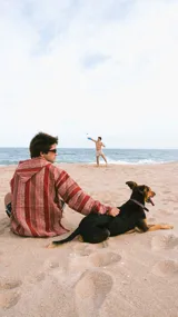 Buzo con capucha de algodón tejido a rayas horizontales en tonos rojo y marrón. Tiene un bolsillo tipo canguro en el frente y cordones ajustables en el cuello. Diseño holgado y estilo relajado.