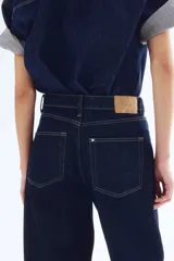 Pantalón de jean azul oscuro de corte holgado, con tiro alto, cinco bolsillos y cierre con botón.