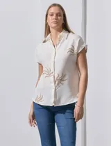 Camisa color beige con estampado de hojas marrones, de manga corta, con cuello a la base con solapa y escote en V.