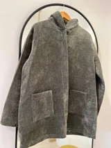 Tapado de pana verde seco, corte recto, con cierre frontal oculto por solapa y bolsillos delanteros. Interior forrado con estampado.