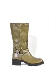 Bota de caña media color verde oliva, con puntera redondeada y taco bajo. Presenta una correa con hebilla metálica alrededor del tobillo y detalles de tachas plateadas.