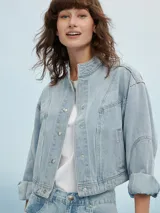 Campera de jean celeste con cuello mao, cierre frontal con botones metálicos y mangas largas con puños abotonados.