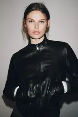 Chaqueta bomber de cuero negra con cuello alto, cierre frontal con cremallera, bolsillos laterales y puños y bajo elásticos.