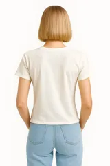 Remera marrón de algodón con estampado de sellos postales con motivos florales, animales y texto. Corte clásico y cuello redondo.