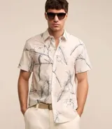 Camisa de hombre confeccionada en voil color crudo con estampa floral estilo outline en azul. Tiene cuello inglés, abotonado delantero y manga corta.