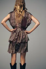Vestido corto con estampado de cachemira en tonos marrones, beige y verde. Tiene escote en pico con abalorios, mangas cortas y cintura elástica con cinturón fino.