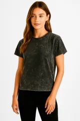 Remera negra de algodón con efecto gastado, corte holgado, cuello redondo y tachas plateadas en los hombros.