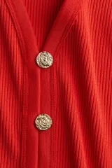 Chaleco rojo en punto suave acanalado, entallado con escote en V y botones de metal con diseño en relieve.