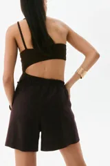 Short marrón de lino con cintura elastizada y cordón ajustable. Presenta pliegues frontales, bolsillos laterales y corte holgado.