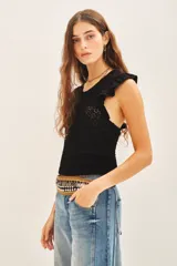 Musculosa negra tejida en hilo de algodón con punto desagujado, calce al cuerpo y volados en las sisas.