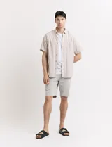 Bermuda de gabardina color verde medio, corte recto, con bolsillos laterales y traseros.