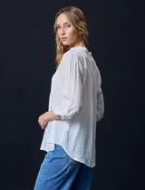 Blusa blanca de gasa bambula, marca Zac & Rachel. Cuello a la base, escote en V con apertura y botones. Largo de manga regulable con presilla y botón.