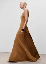 Vestido largo de tejido de punto fino color camel, sin mangas y con cuello redondo. Presenta un corte evasé que se ajusta al cuerpo en la parte superior y cae con vuelo en la falda.