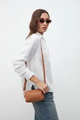 Bandolera rectangular color marrón, con correa larga ajustable y cierre superior con cremallera dorada.