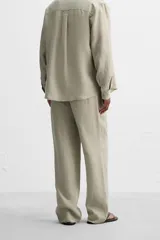 Pantalón negro regular fit confeccionado en tejido de lino. Cintura ajustable con cordón interior, bolsillos frontales y detalle de bolsillos traseros de vivo.