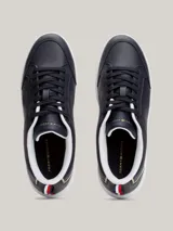 Zapatillas Tommy Hilfiger de cuero azul marino con suela blanca, cordones negros, interior blanco y detalles dorados en el talón y en el lateral.