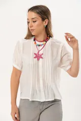 Blusa blanca de mangas cortas con cuello redondo y abotonadura frontal.