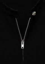 Vestido corto negro de tejido de punto fino, con cuello redondo, diseño recto y cierre delantero con cremallera metálica.