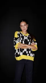 Sweater de punto con mangas cortas, estampado geométrico en blanco y negro, y ribetes amarillos en cuello, puños y ruedo.