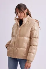Campera puffer color beige de poliéster con capucha, cierre frontal con cremallera y bolsillos laterales.