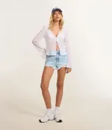 Short de jeans azul claro, modelo slim fit, con roturas y terminación deshilachada en el ruedo. Presenta tiro medio/alto con trabillas para cinturón y cierre frontal tradicional.