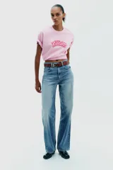 Camiseta rosa de algodón con efecto lavado, corte regular, cuello redondo y mangas cortas. Estampado frontal con la frase "Puerto Rico Vuela Conmigo".