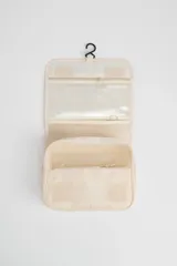 Neceser de viaje color beige con cierre de cremallera y asa de mano. Tiene un pequeño logo rectangular en el frente.