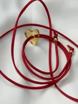 Collar con cordón rojo ajustable y dije de corazón transparente.