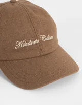 Gorra de béisbol color beige con visera marrón, bordado frontal con la inscripción "Wednesday 1996" y regulador metálico trasero.