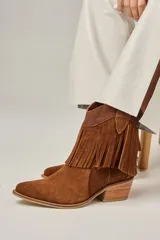 Bota tejana de cuero vacuno color beige con flecos en la caña, taco de 5.5 cm y caña de 17 cm.