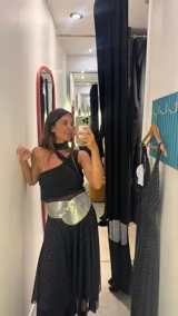 Vestido midi negro con estampado de lunares blancos, breteles finos y falda con volados y transparencias.