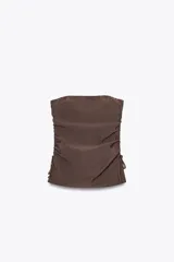 Top marrón sin tirantes confeccionado en tejido fluido, con escote recto, detalle de frunces ajustables con cordones en los laterales y bajo con aberturas laterales.